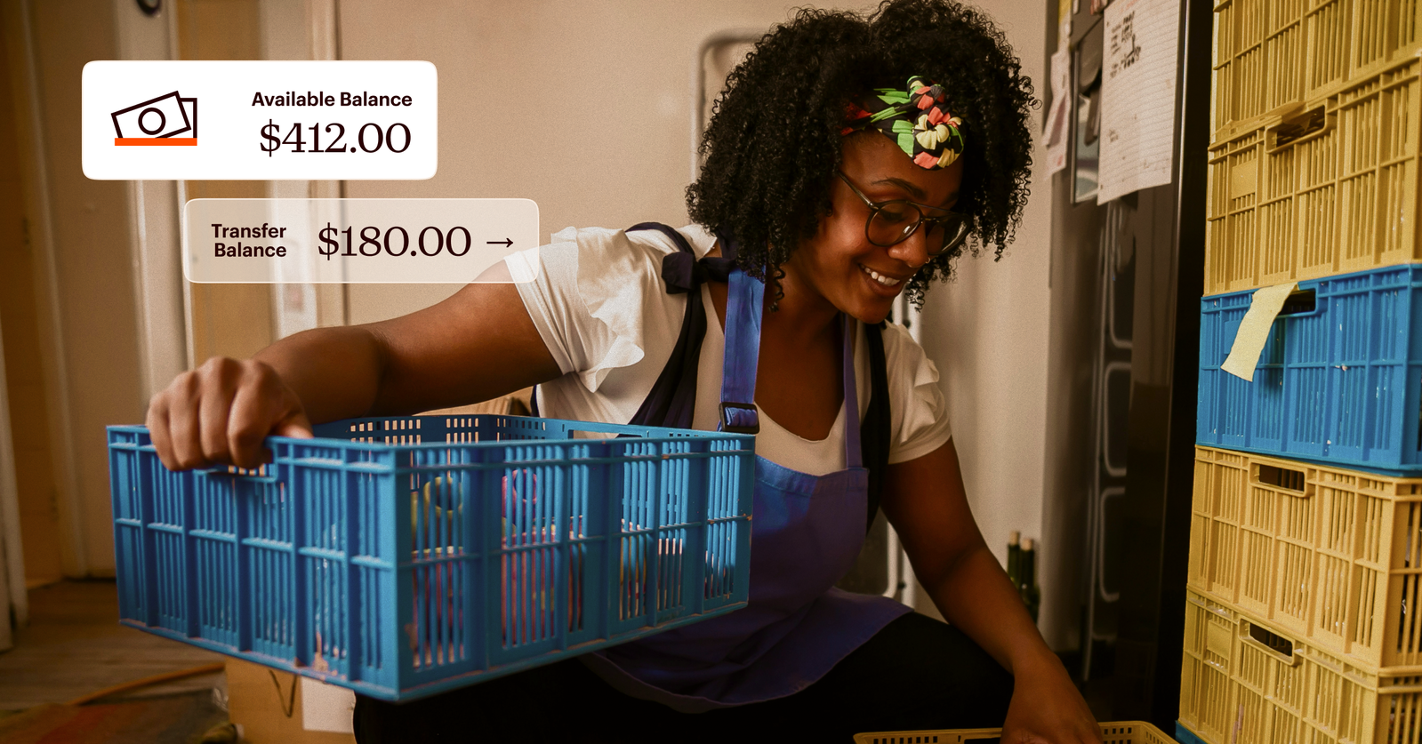 A person wearing an apron handles blue crates indoors. Overlaid graphics show an available balance of $412.00 and a transfer balance of $180.00.