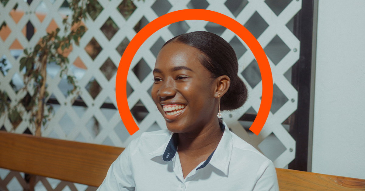 A woman sits on a wooden bench, smiling, with an orange semicircle graphic behind her head and a white lattice background, embodying the positivity that comes from employee financial wellness.