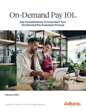 Cover of an informational guide titled "On-Demand Pay 101." The subheading reads "Key Considerations to Jump Start Your On-Demand Pay Evaluation Process." It features a man and a woman working on a laptop in a plant-filled cafe. The guide is dated February 2023 and is branded by DailyPay.