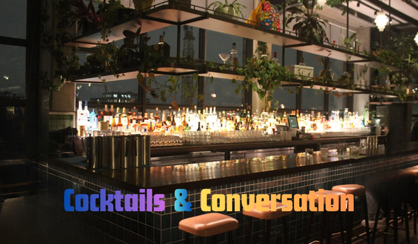 A modern bar with bottles on shelves, plants, and stools at the counter, with the text "Cocktails & Conversation" in colorful font across the image.