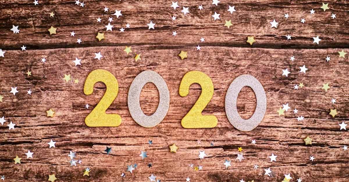 Wooden surface adorned with gold and silver star confetti, with the numbers "2020" placed centrally in a glittery gold and silver design.