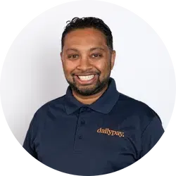 A man with a beard and short hair, wearing a navy blue polo shirt with "DailyPay" embroidered, smiles at the camera against a white background.