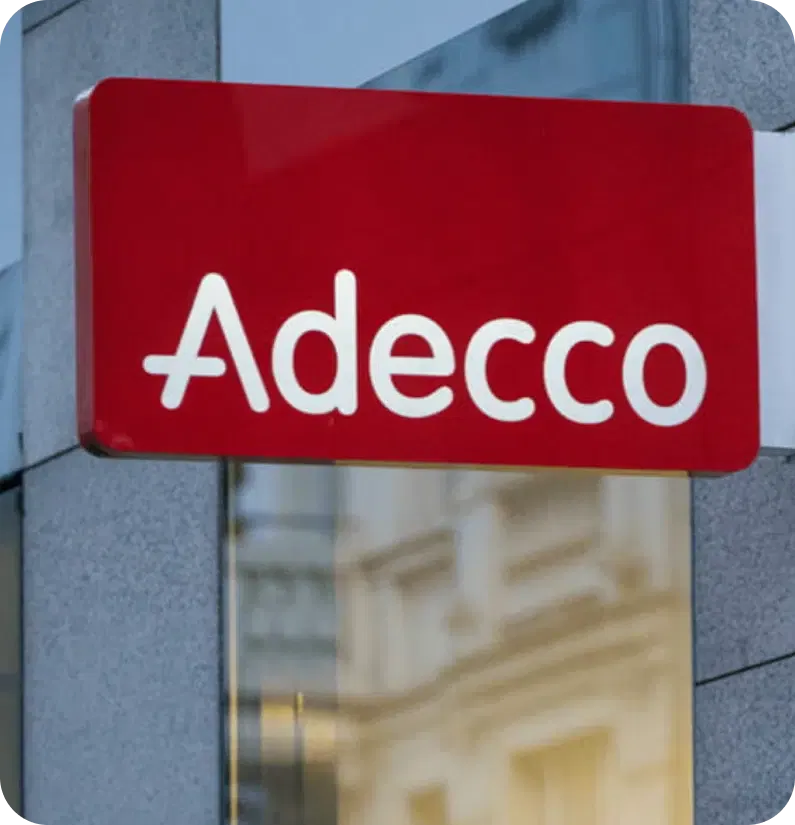 A red sign with white text reading "Adecco" is mounted on a gray building.